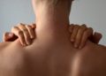 Frau von hinten fasst sich an die Nackenmuskulatur