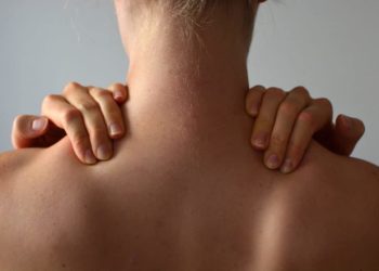 Frau von hinten fasst sich an die Nackenmuskulatur
