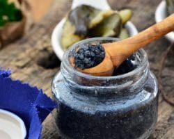 Holzlöffel hebt schwarzes Salz aus Glas