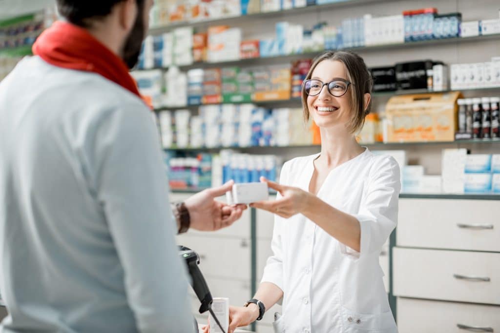 Lächelnde Apothekerin bedient einen Mann