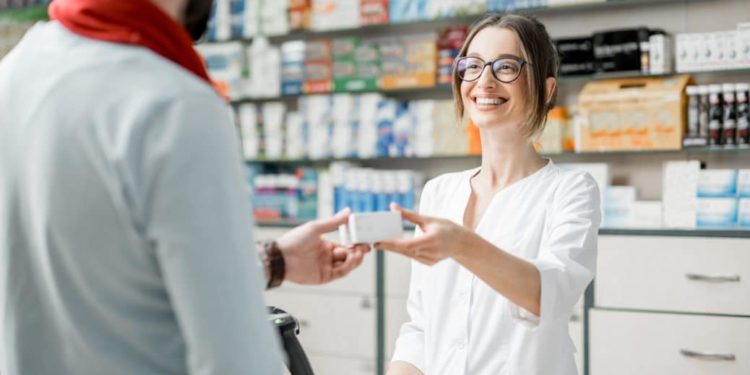 Lächelnde Apothekerin bedient einen Mann