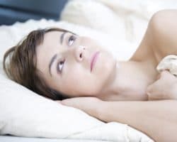 Junge Frau liegt mit geöffneten Augen im Bett