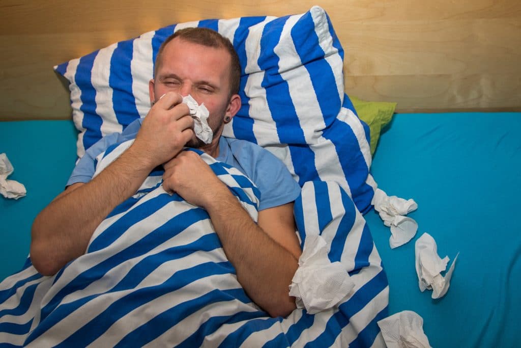 Mann liegt erkältet im Bett