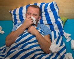 Mann liegt erkältet im Bett
