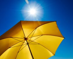Gelber Sonnenschirm von unten mit Blick zum blauen Himmel