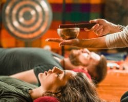 Mann und Frau liegen auf dem Boden und erhalten Klangtherapie