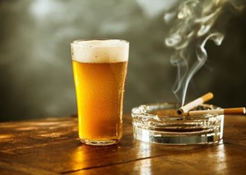 Volles Glas Bier und und brennende Zigaretten im Aschenbecher