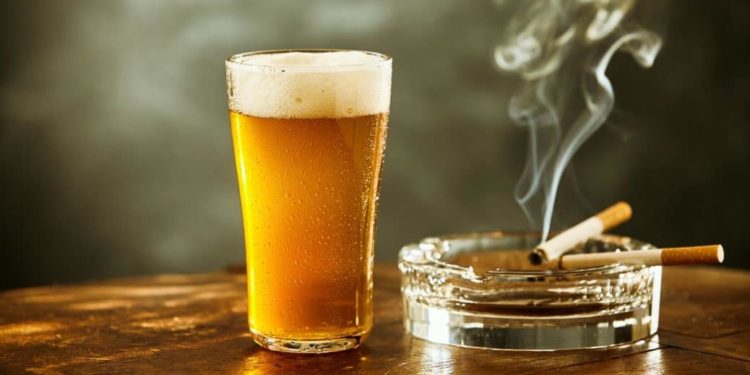 Volles Glas Bier und und brennende Zigaretten im Aschenbecher