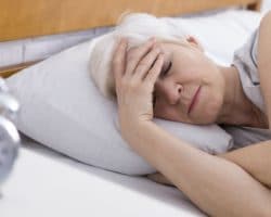Ältere Frau liegt müde im Bett