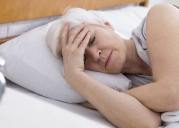 Ältere Frau liegt müde im Bett