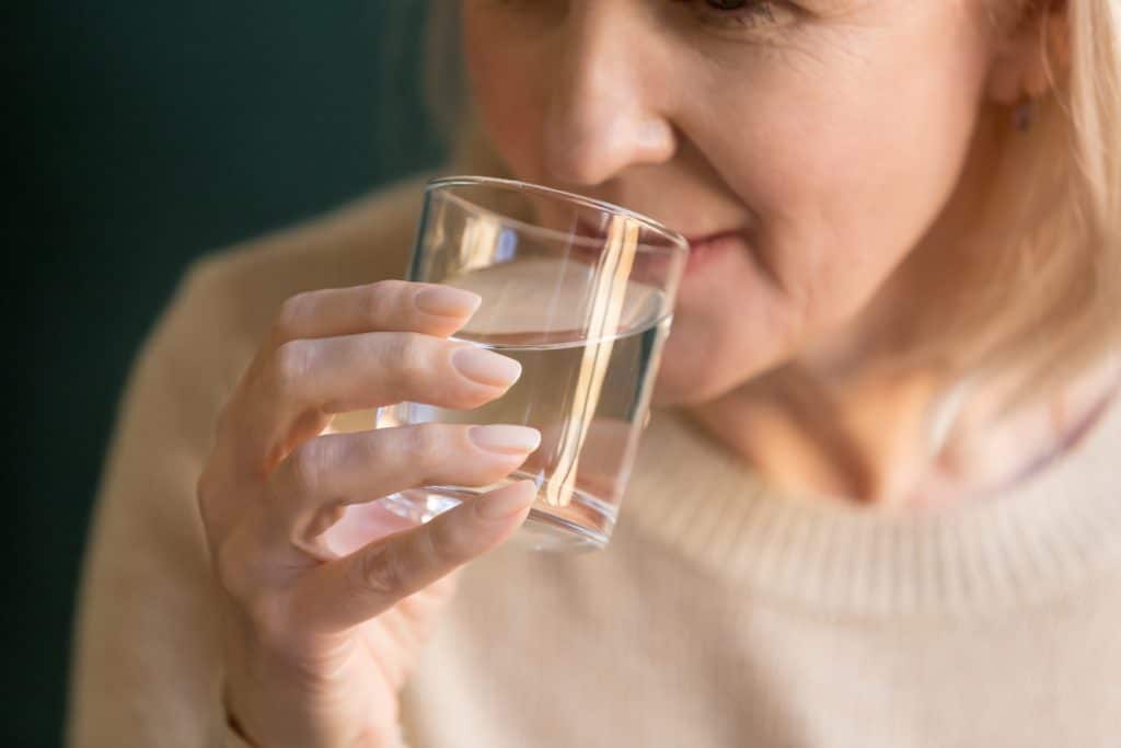 Eine Frau trinkt Wasser aus einem Glas.