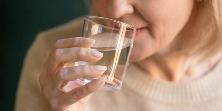 Eine Frau trinkt Wasser aus einem Glas.