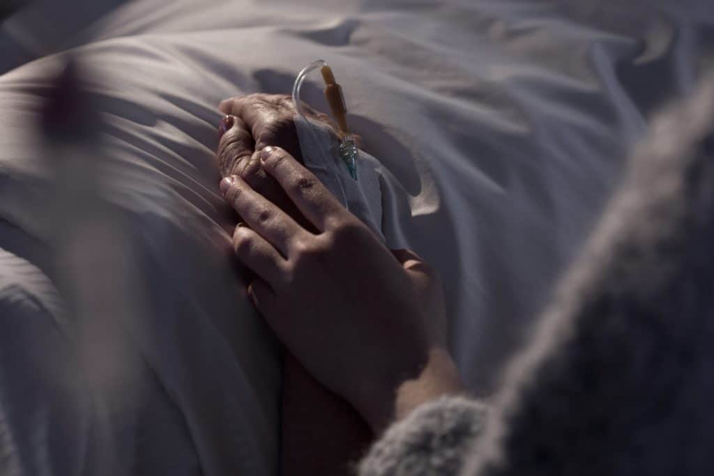 Hände halten am Krankenbett