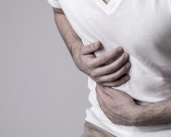 Mann krümmt sich vor Übelkeit.