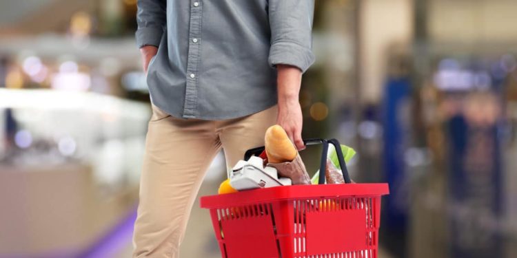 Mann mit gefülltem Einkaufskorb im Supermarkt