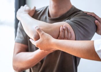 Ärztin untersucht Oberarm eines Mannes.