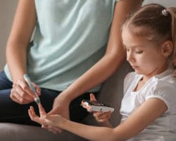 Mutter nimmt von ihrer zuckerkranken Tochter eine Blutprobe mit einem Insulin-Pen