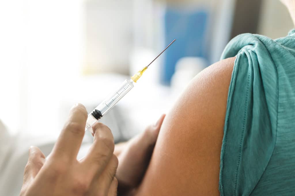 Arzt bereitet Impfung in den Oberarm eines Patienten vor