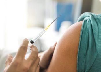 Arzt bereitet Impfung in den Oberarm eines Patienten vor