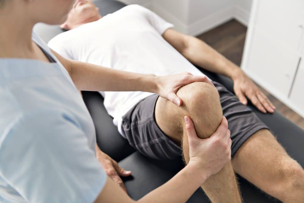 Mann während  Physiotherapie am Knie