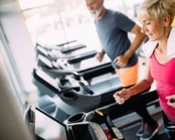 Zwei ältere Menschen laufen auf einem Laufband im Fitnesscenter