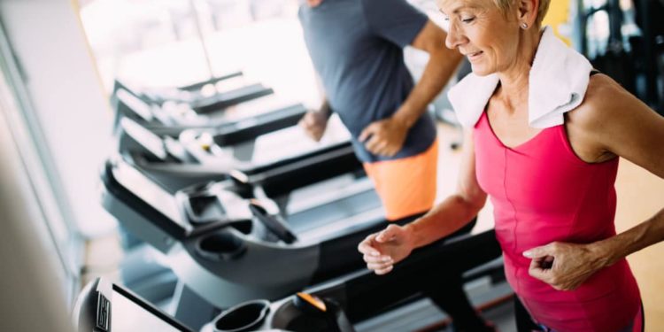 Zwei ältere Menschen laufen auf einem Laufband im Fitnesscenter