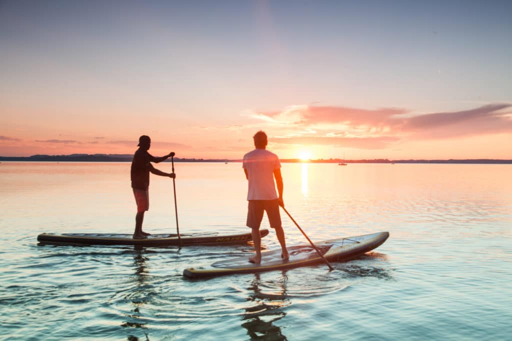 Zwei Männer beim Stand-up-paddling auf einem See