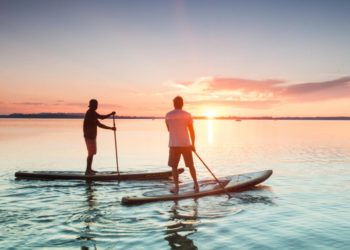 Zwei Männer beim Stand-up-paddling auf einem See