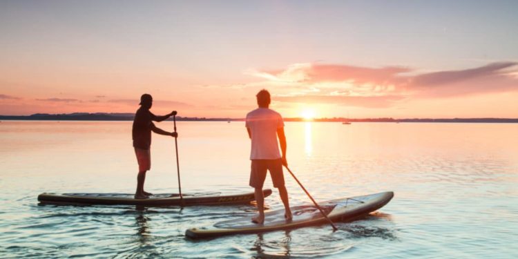 Zwei Männer beim Stand-up-paddling auf einem See