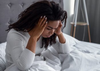 Frau sitzt nach dem Aufwachen im Bett.