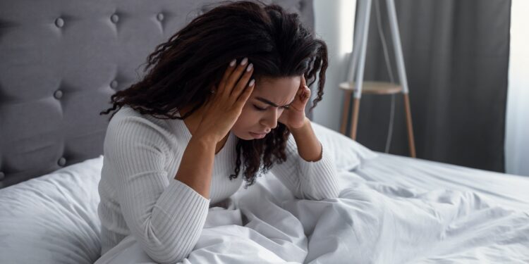 Frau sitzt nach dem Aufwachen im Bett.