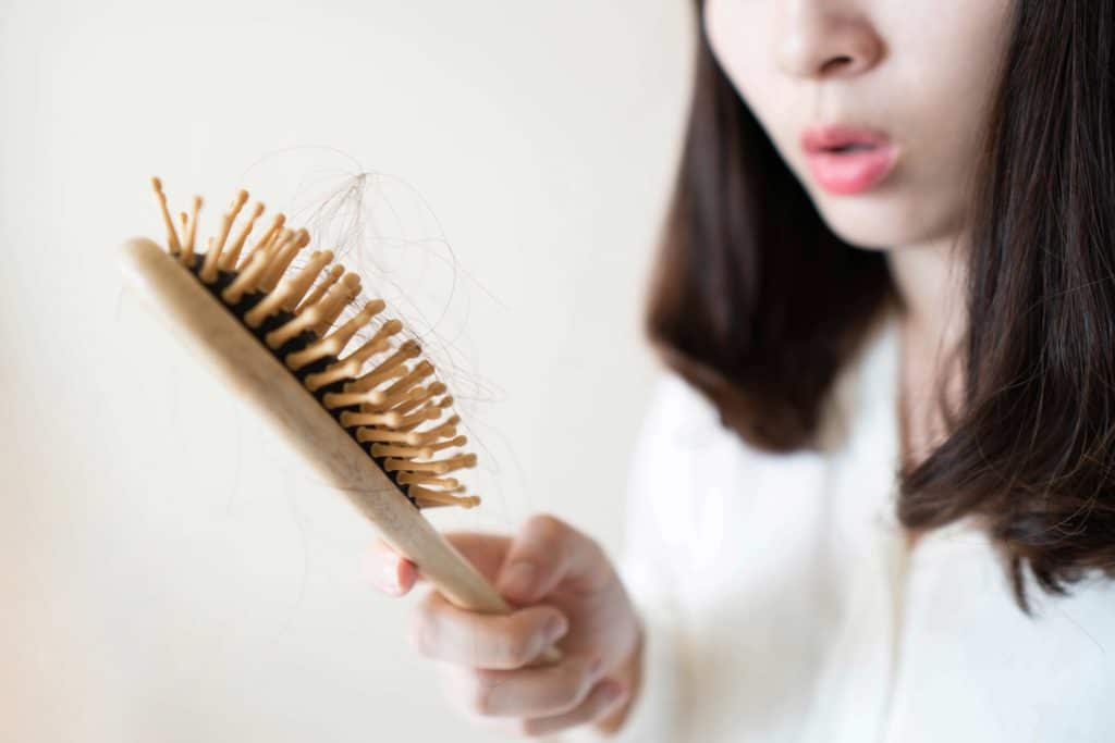 Frau guckt die Haarbürste an