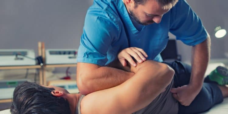 Ein Chiropraktiker führt eine Behandlung bei einem Mann durch.
