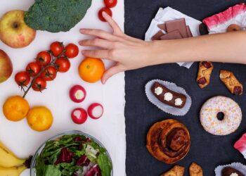 Verschiedene Lebensmittel auf weißem und schwarzem Untergrund und eine Hand, die eine Mandarine greift