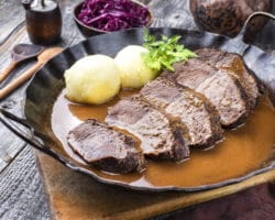 Sauerbraten und Kartoffelknödel in einer Pfanne mit Sauce