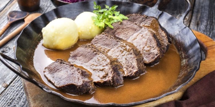 Sauerbraten und Kartoffelknödel in einer Pfanne mit Sauce