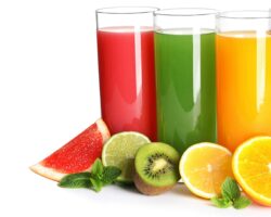 Verschiedene Fruchtsäfte in Gläsern mit einigen Obststücken als Deko am Fuß der Gläser