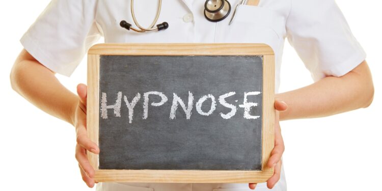 Ärztin hält Schiefertafel mit der Aufschrift Hypnose in den Händen