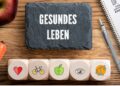 Aufschrift gesundes Leben einige Symbole, gesunde Nahrungsmittel und ein Stift und Block