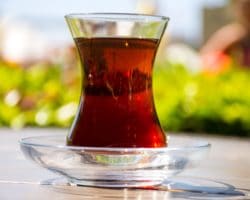 Kleines Teeglas gefüllt mit schwarzem Tee.