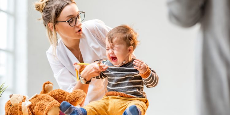 Eine Ärztin untersucht ein schreiendes Baby.