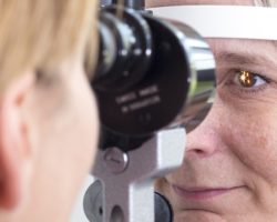Eine Augenärztin untersucht die Augen einer Frau mithilfe der Spaltlampe.