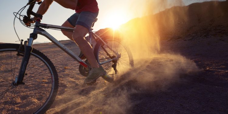Ein Mann fährt mit einem Mountainbike durch eine staubige Wüste. 