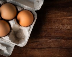 Braune Eier in einem Eierkarton, der auf einem Holztisch steht