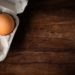 Braune Eier in einem Eierkarton, der auf einem Holztisch steht
