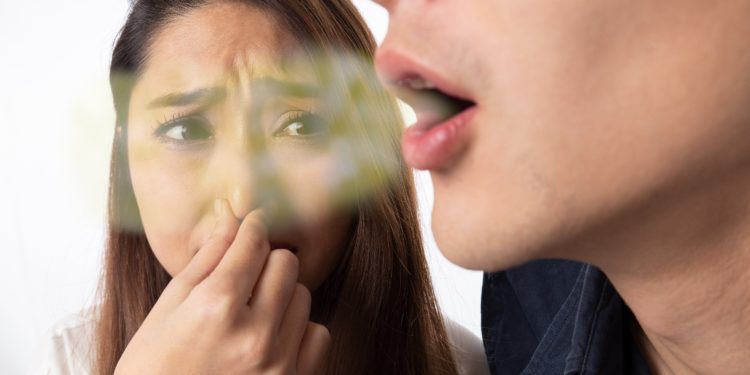 Eine junge Frau hält sich aufgrund des schlechten Atems ihres Partners die Nase zu.