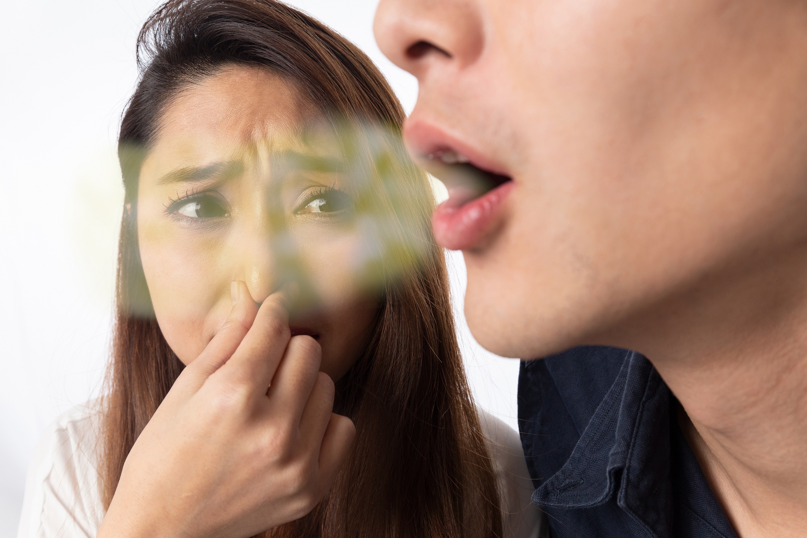 Eine junge Frau hält sich aufgrund des schlechten Atems ihres Partners die Nase zu.