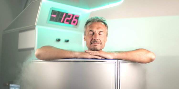 Ein Mann sitzt in einer Kältesauna, die auf einem Display eine Temperatur von minus 126 Grad Celsius anzeigt. 