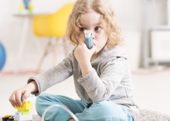Ein junges Mädchen benutzt einen Asthma-Inhalator.