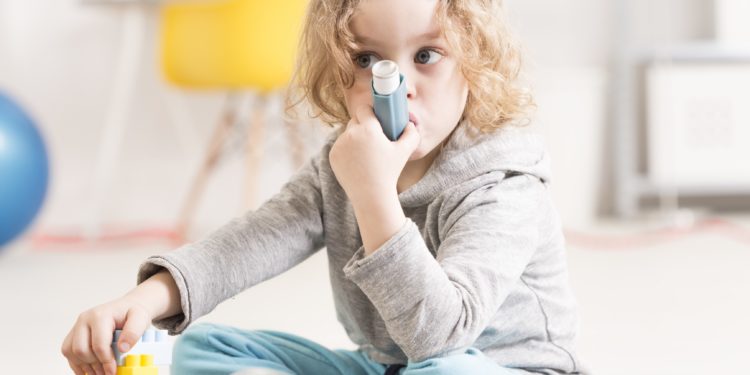 Ein junges Mädchen benutzt einen Asthma-Inhalator.